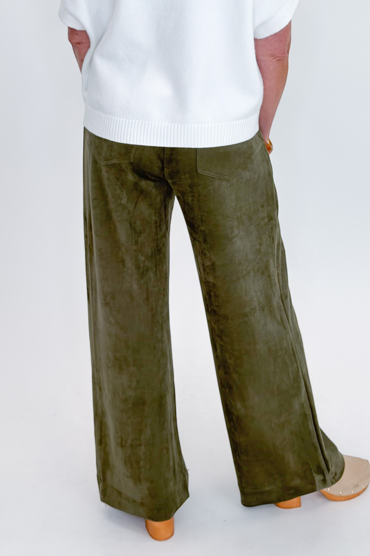 Back view of woman wearing Swagger Boutique’s sweater with Olive Suede Wide Leg Pants against white studio background.