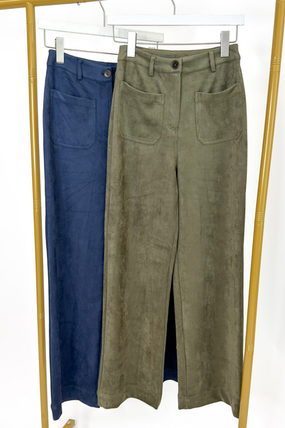 Swagger Boutique’s sweater with Olive Suede Wide Leg Pants and Navy Suede pants hanging against white studio background.