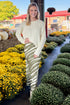 Front view of woman wearing Swagger Boutique’s Olive Zebra Print Satin Skirt with sweater at a garden center. 