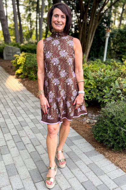 Front view of woman wearing Swagger Boutique’s Olive &amp; Brown Floral Halter Neck Mini Dress walking down a path outside.