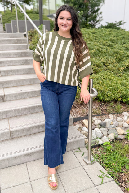 Front view of woman wearing Swagger Boutique’s Olive &amp; Cream Striped Short Sleeve Sweater by Entro with jeans walking outside down a path.