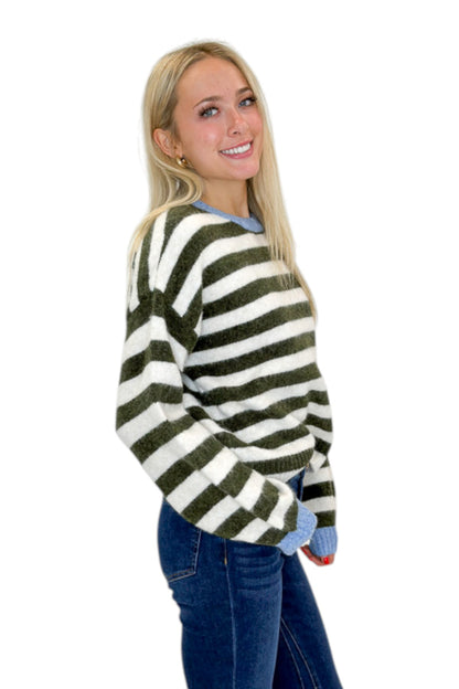 Side view of woman wearing Swagger Boutique’s Olive &amp; Cream Striped Sweater by Entro with jeans against white studio background.