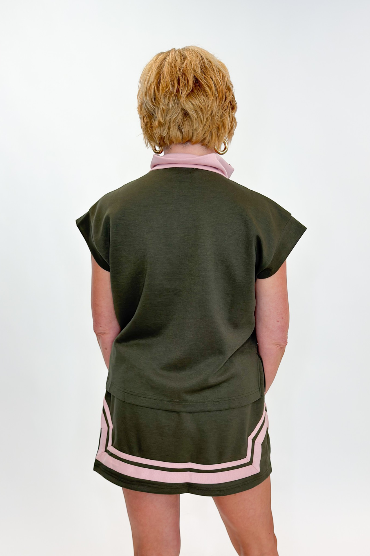 Back view of woman wearing Swagger Boutique’s Olive &amp; Pink Half Zip Top &amp; Skirt by Entro against white studio background.