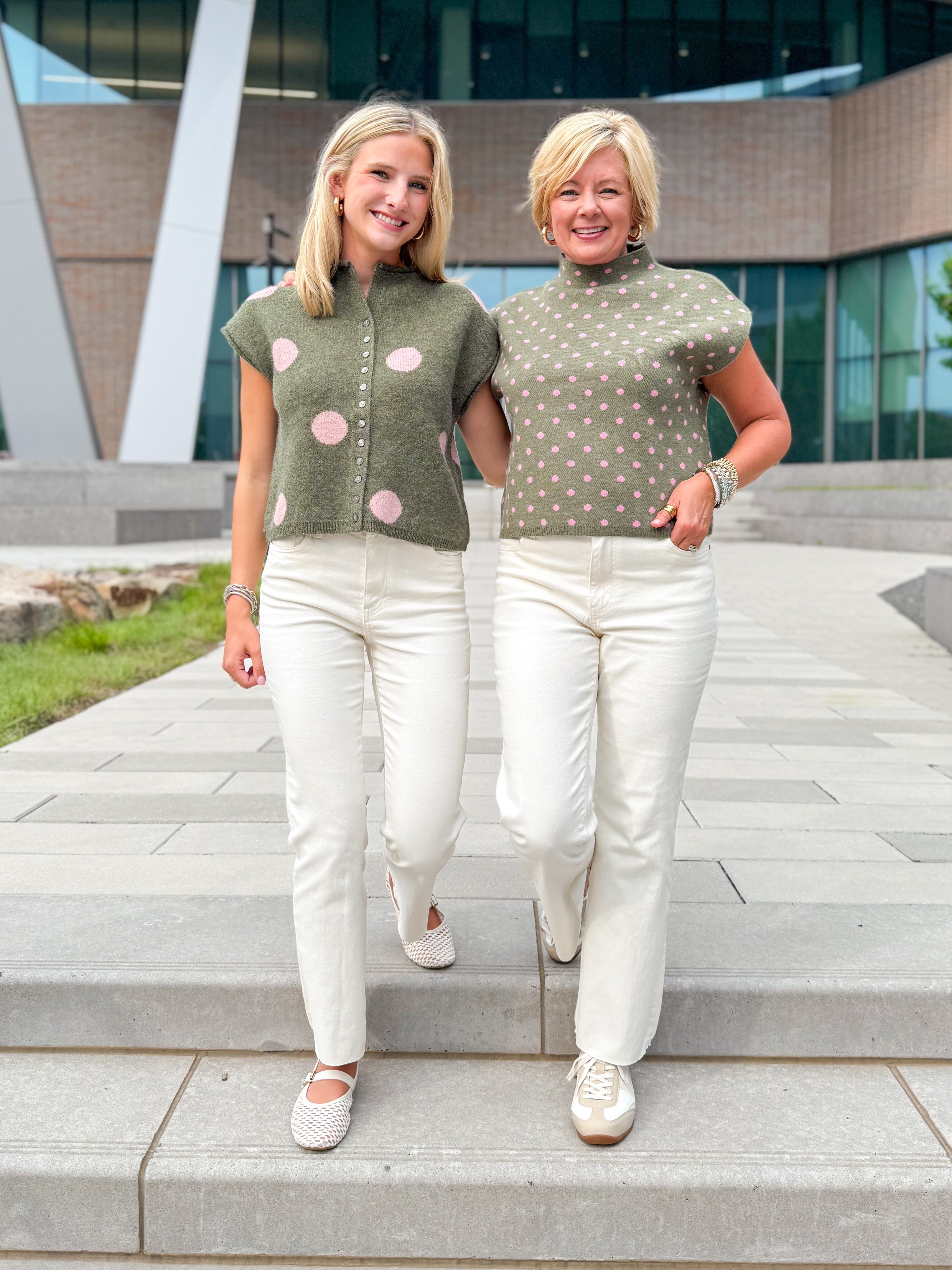 Front view of women wearing Swagger Boutique’s Olive &amp; Pink Polka Dot Sweaters by Entro with jeans walking down a staircase outside.