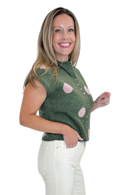 Side view of woman wearing Swagger Boutique’s Olive &amp; Pink Polka Dot Sleeveless Button Up Sweater by Entro with jeans against white studio background.
