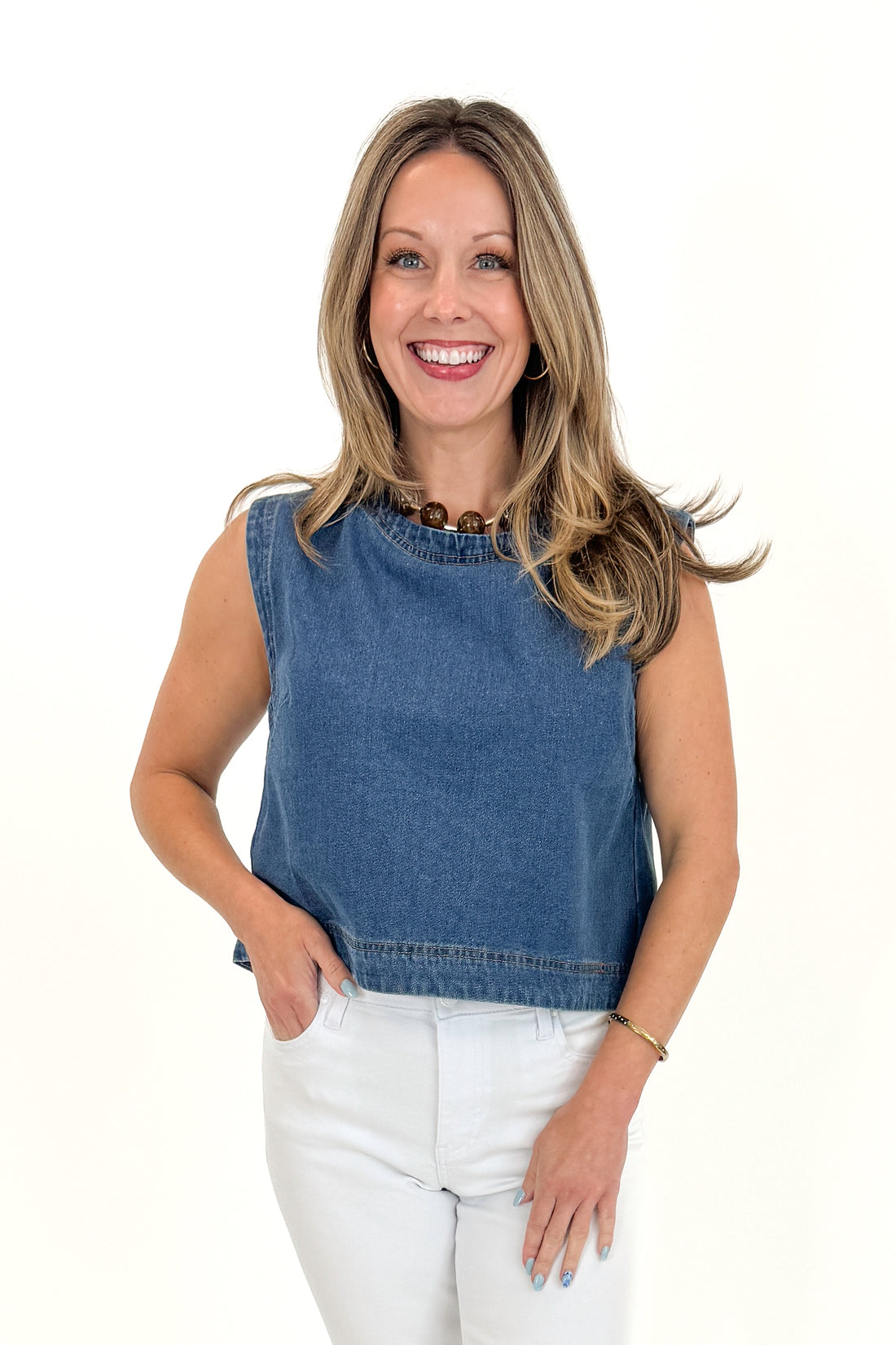 Front view of woman wearing Medium Wash Denim Top with jeans against white studio background.
