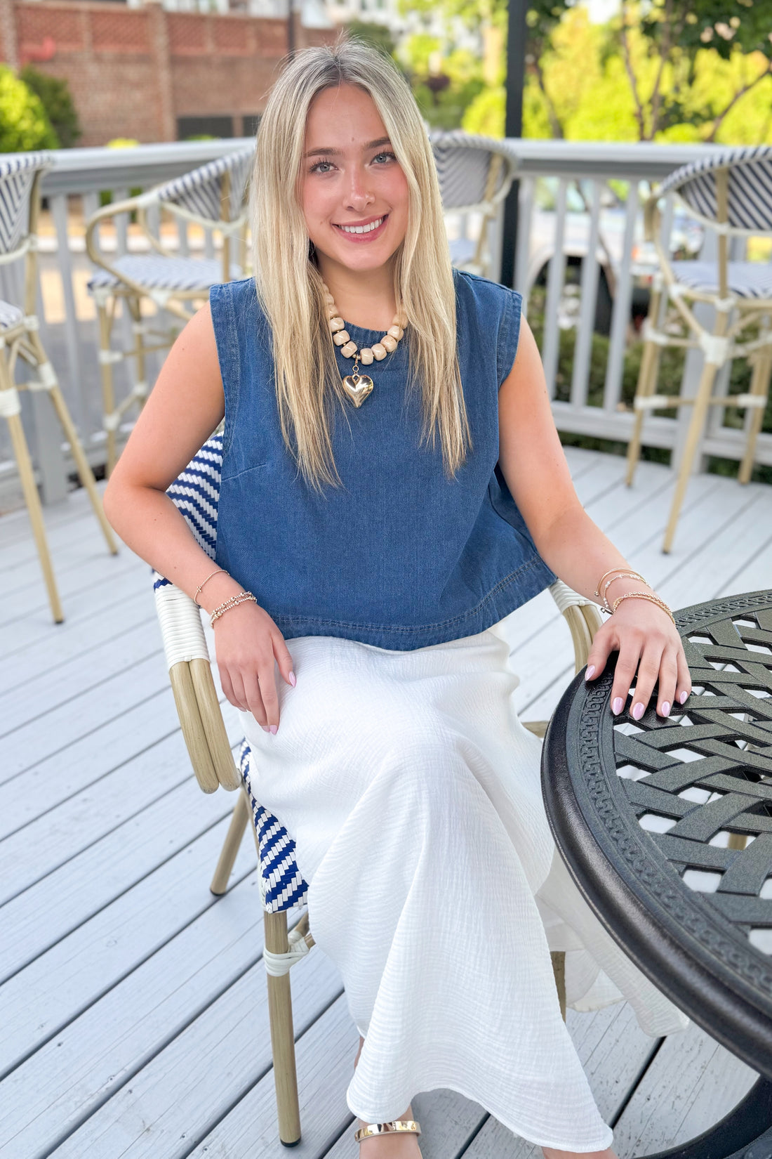 Front view of woman wearing Medium Wash Denim Top with jeans outside at a restaurant.