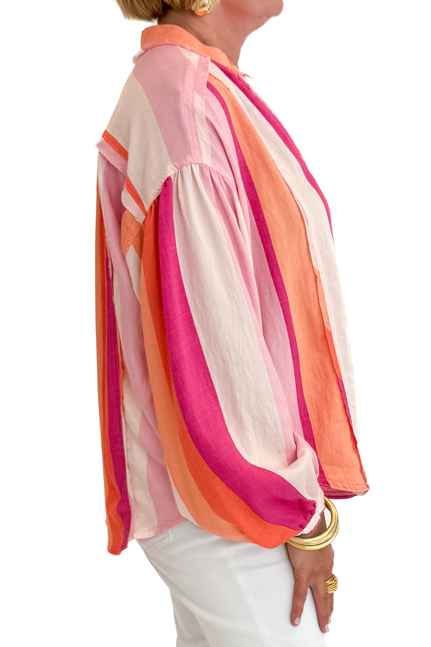 Side detail view of woman wearing Swagger Boutique’s Orange &amp; Pink Striped Top with jeans against white studio background.