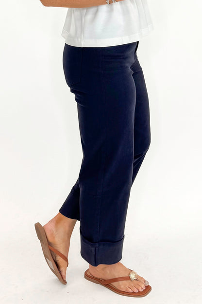 Side detail view of woman wearing Navy Cuffed Jeans by Entro with white top against white studio background.