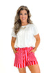 Front view of woman wearing Pink & Orange Striped Shorts by Entro with white top against white studio background.