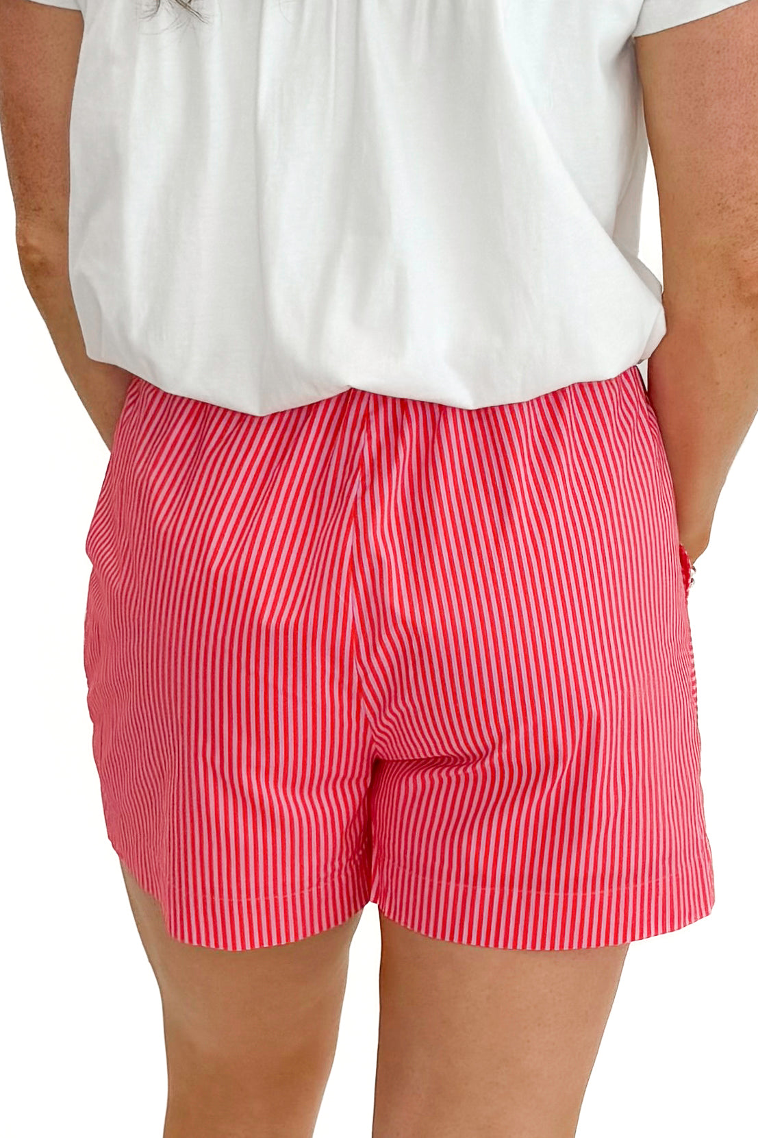Back view of woman wearing Pink &amp; Orange Striped Shorts by Entro with white top against white studio background.