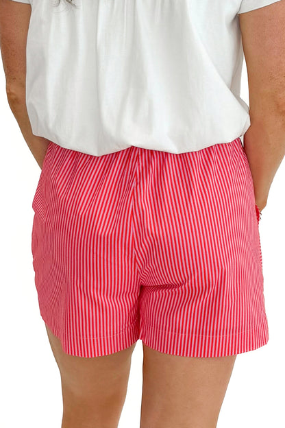 Back view of woman wearing Pink &amp; Orange Striped Shorts by Entro with white top against white studio background.