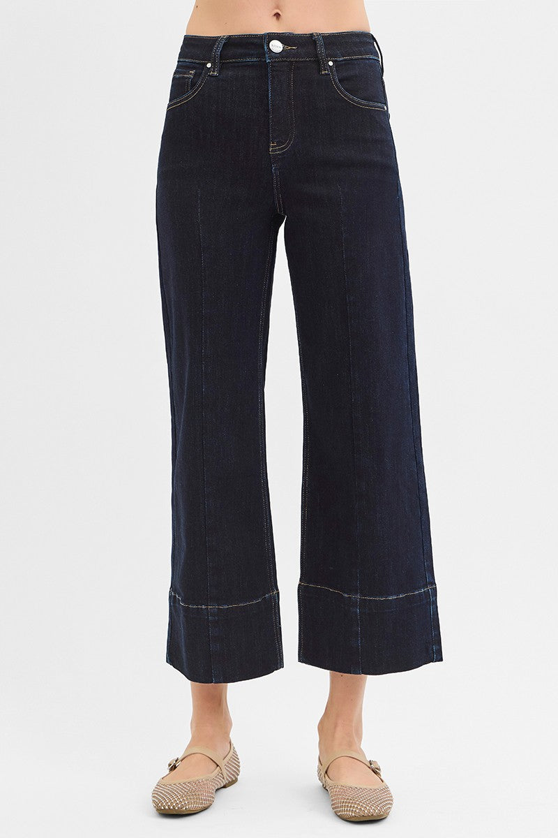 Dark blue jeans worn by a person on a white background