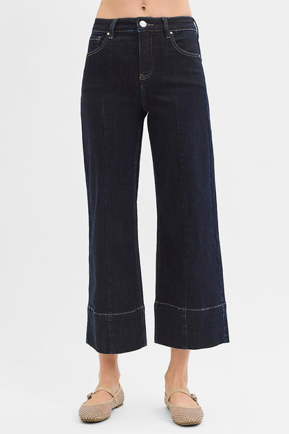 Dark blue jeans worn by a person on a white background