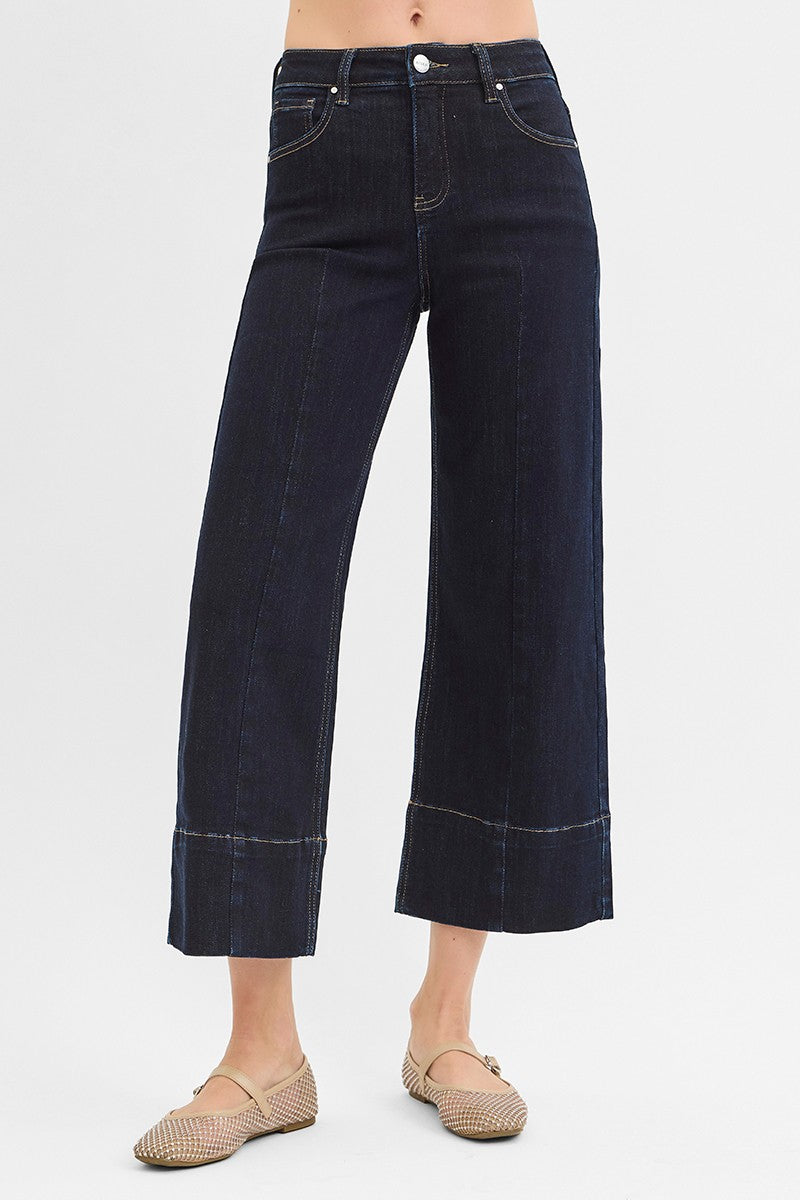 Dark blue wide-leg jeans worn by a person on a light gray background
