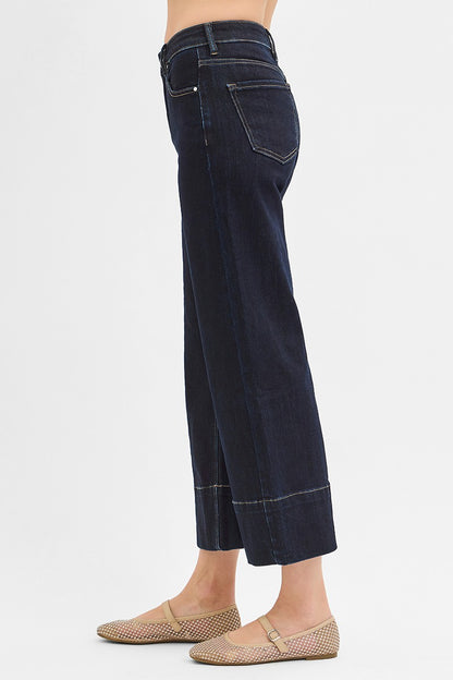 Dark blue jeans worn by a person on a white background