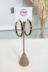 Tortoiseshell hoop earrings displayed on a burlap-covered stand with a white card labeled &