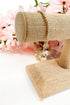 Gold bracelet on a decorative stand with pink flowers in the background