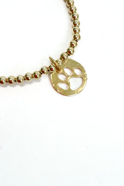 Gold beaded bracelet with a paw print charm on a white background