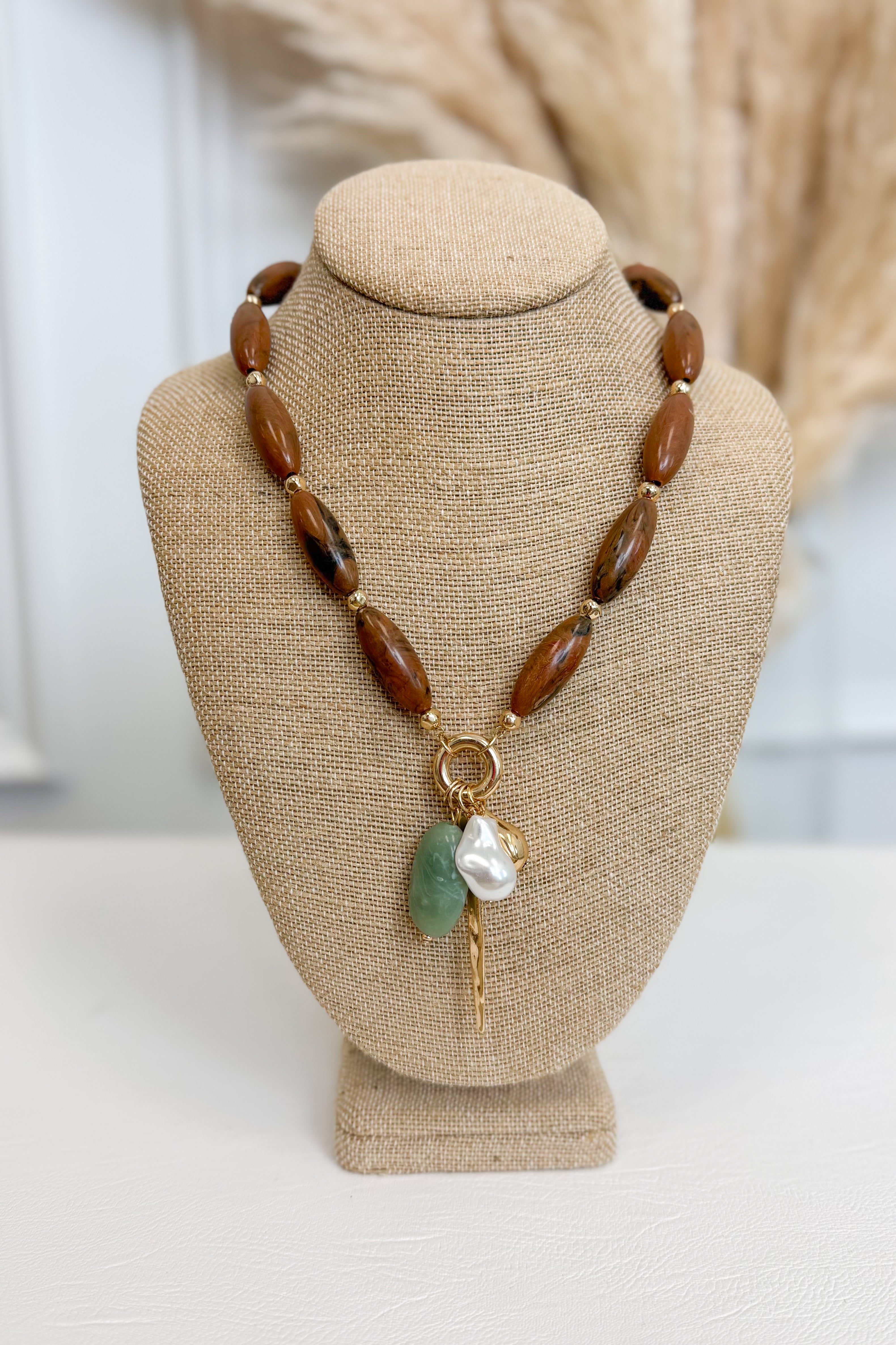 front view of brown necklace with pearl, sea-foam, and gold accent charms on bust