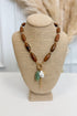 front view of brown necklace with pearl, sea-foam, and gold accent charms on bust