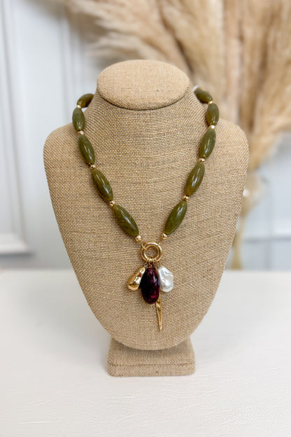 front view of olive necklace with pearl, plum, and gold accent charms on bust