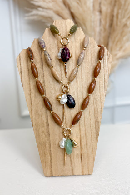 front view of all three marble stone multi charm necklaces necklaces with pearl, plum, sea-foam, and gold accent charms on wooden bust 