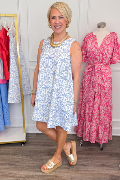 Woman wearing Pinch Blue Tropical Printed Mini Dress and sandals side view.