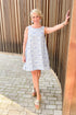 Woman wearing Pinch Blue Tropical Printed Mini Dress and sandals standing outside.