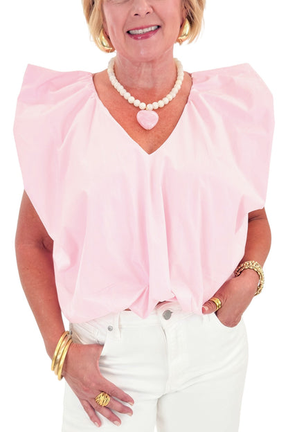 Front detail view of woman wearing Swagger Boutique’s Pink Bubble Hem Pleated Top with jeans against white studio background.