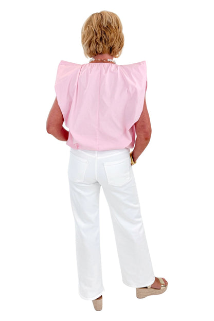 Back view of woman wearing Swagger Boutique’s Pink Bubble Hem Pleated Top with jeans against white studio background.