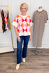 Front view of woman wearing Swagger Boutique’s Pink Color Block Short Sleeve Sweater with jeans with clothing hanging in the background.
