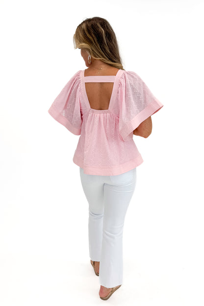 Back view of woman wearing Swagger Boutique’s Pink Eyelet V-Neck Top with jeans against white studio background.