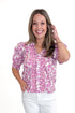 Front view of woman wearing Pink Floral Button Up Top with jeans against white studio background.