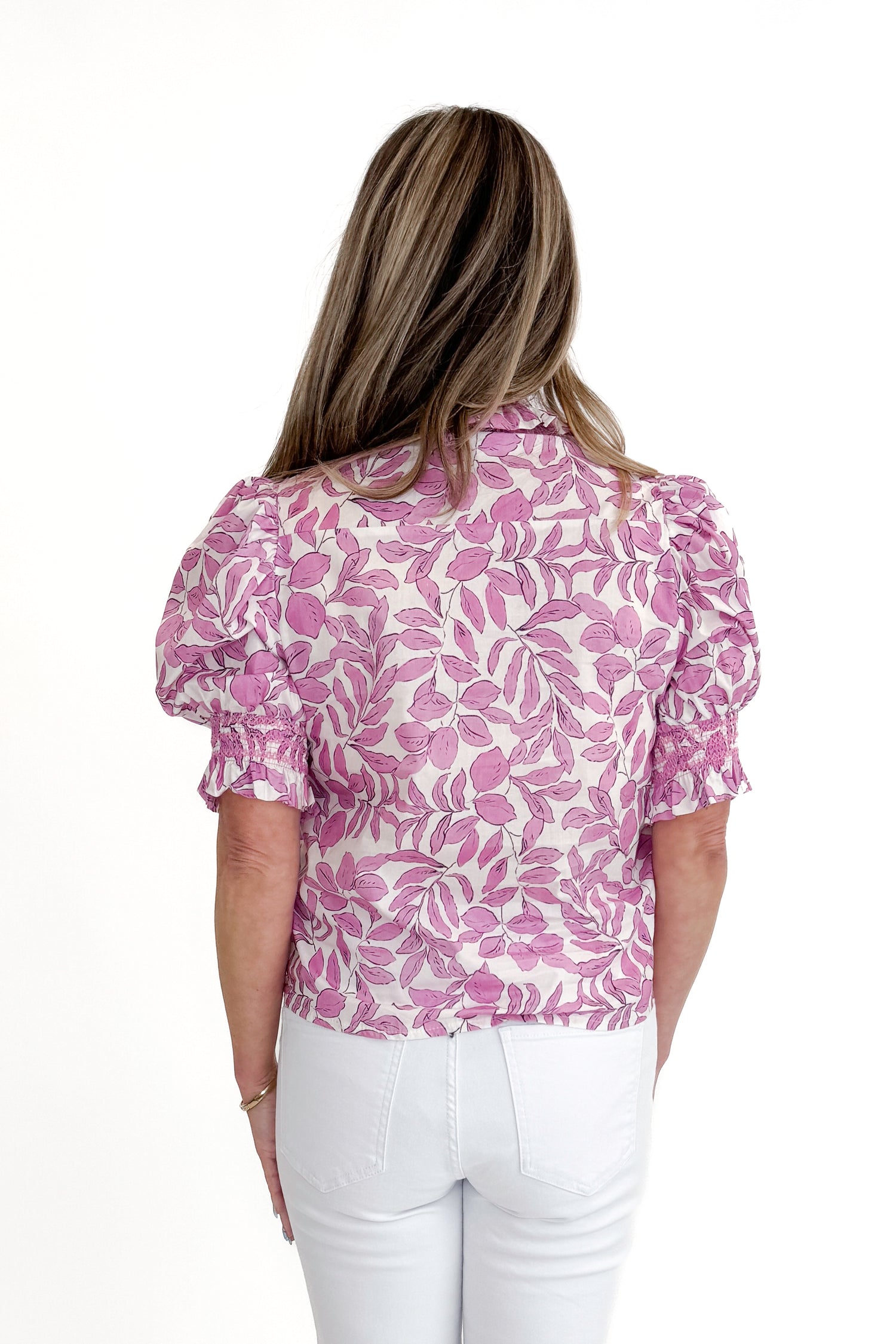 Back view of woman wearing Pink Floral Button Up Top with jeans against white studio background.