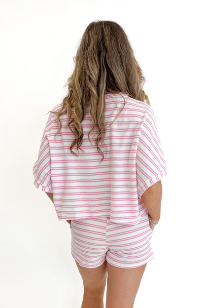 Back view of woman wearing Swagger Boutique’s Pink Striped Terry Cloth Top with matching Pink Striped Terry Cloth Shorts against white studio background.