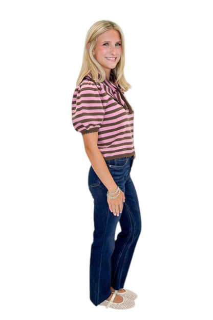 Side view of woman wearing Swagger Boutique’s Pink &amp; Brown Striped Faux Tie Short Sleeve Sweater by Entro with jeans against white studio background.