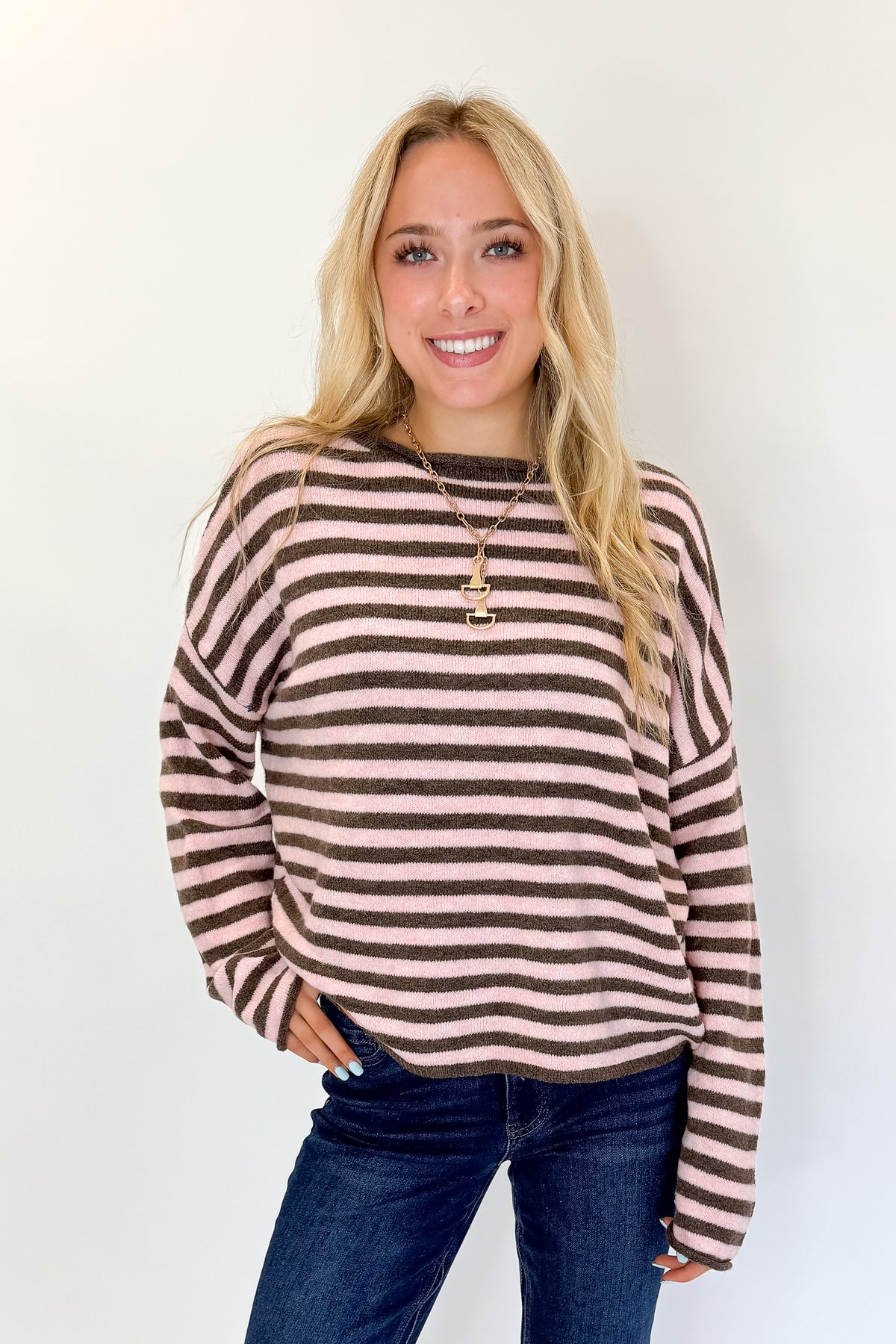 Front view of woman wearing Swagger Boutique’s Pink &amp; Brown Striped Sweater with jeans against white studio background.