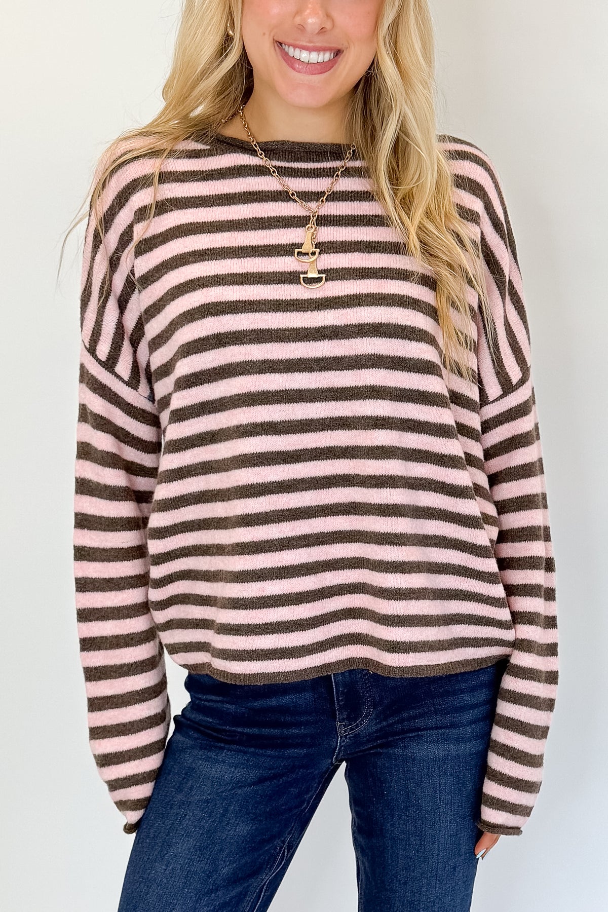 Front detail view of woman wearing Swagger Boutique’s Pink &amp; Brown Striped Sweater with jeans against white studio background.