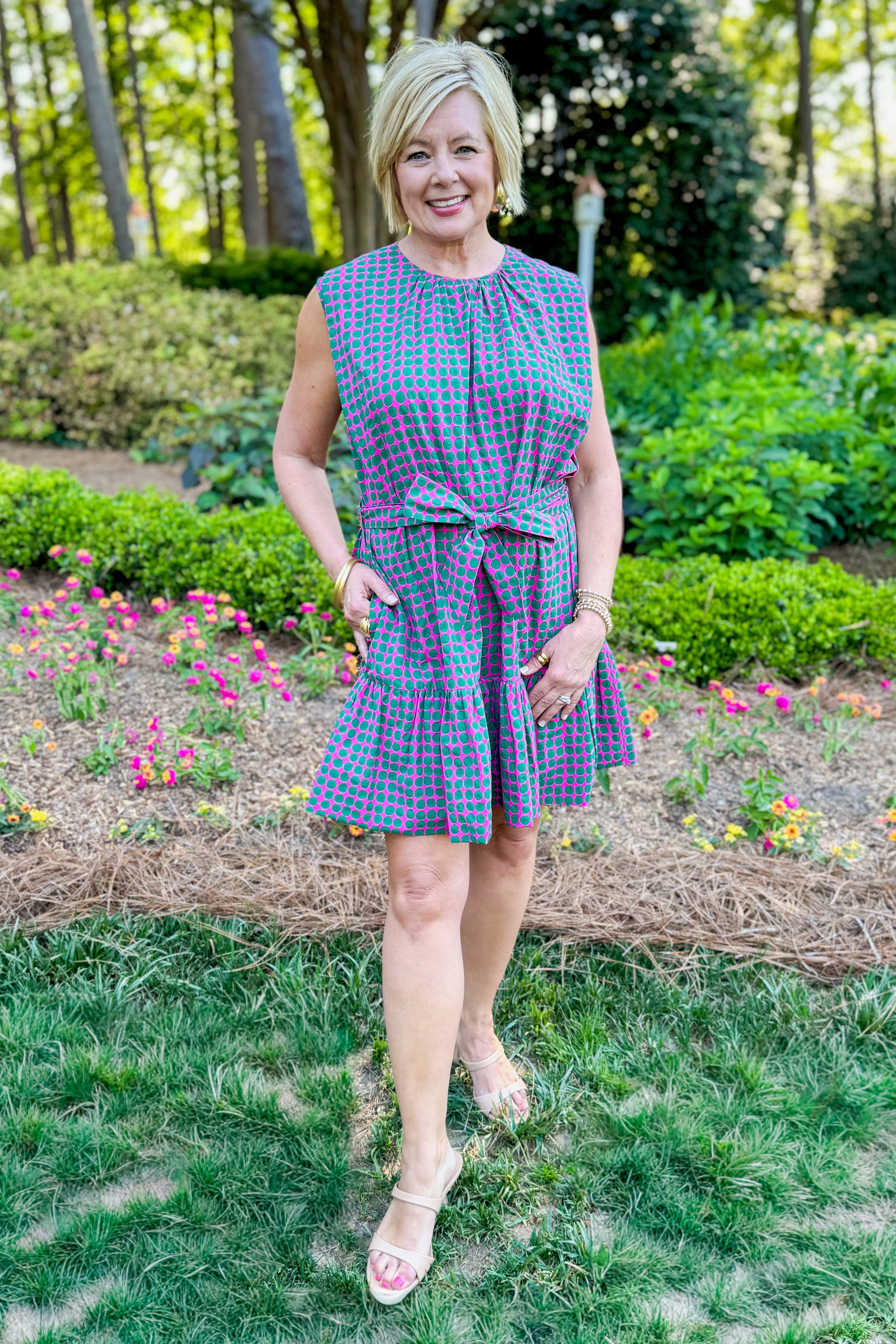 Front view of woman wearing Swagger Boutique’s Pink &amp; Green Polka Dot Mini Dress with heels standing outside.