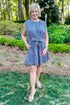Front view of woman wearing Swagger Boutique’s Pink & Green Polka Dot Mini Dress with heels standing outside.