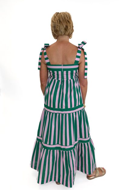 Back view of woman wearing Swagger Boutique’s Pink &amp; Green Striped Tiered Maxi Dress with sandals against white studio background.