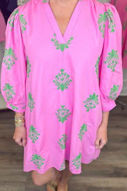 Front detail view of woman wearing Swagger Boutique’s Pink &amp; Green 3/4 Sleeve Embroidered Dress with sandals with clothes around her.