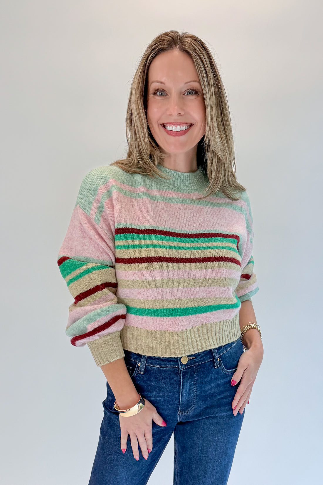 Front view of woman wearing Swagger Boutique’s Pink &amp; Multi Striped Sweater with jeans against white studio background.