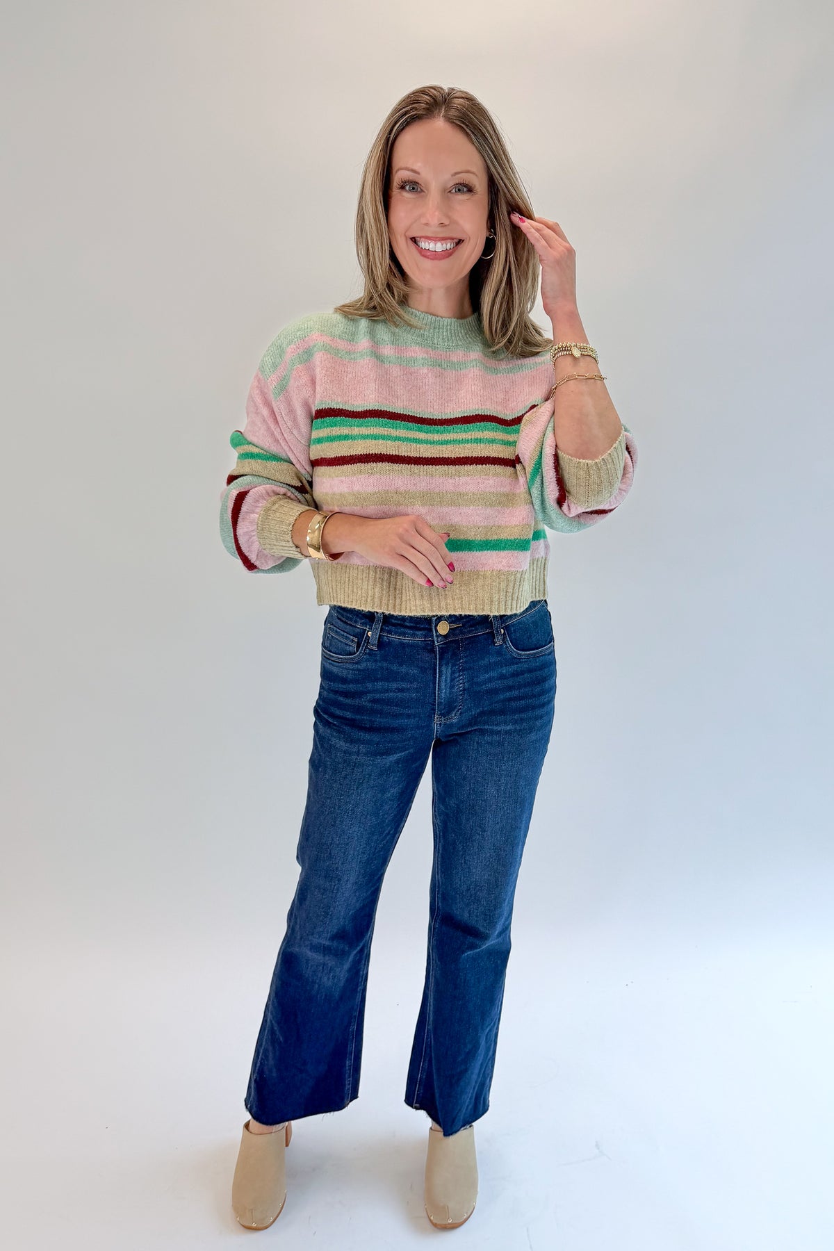 Front view of woman wearing Swagger Boutique’s Pink &amp; Multi Striped Sweater with jeans against white studio background.