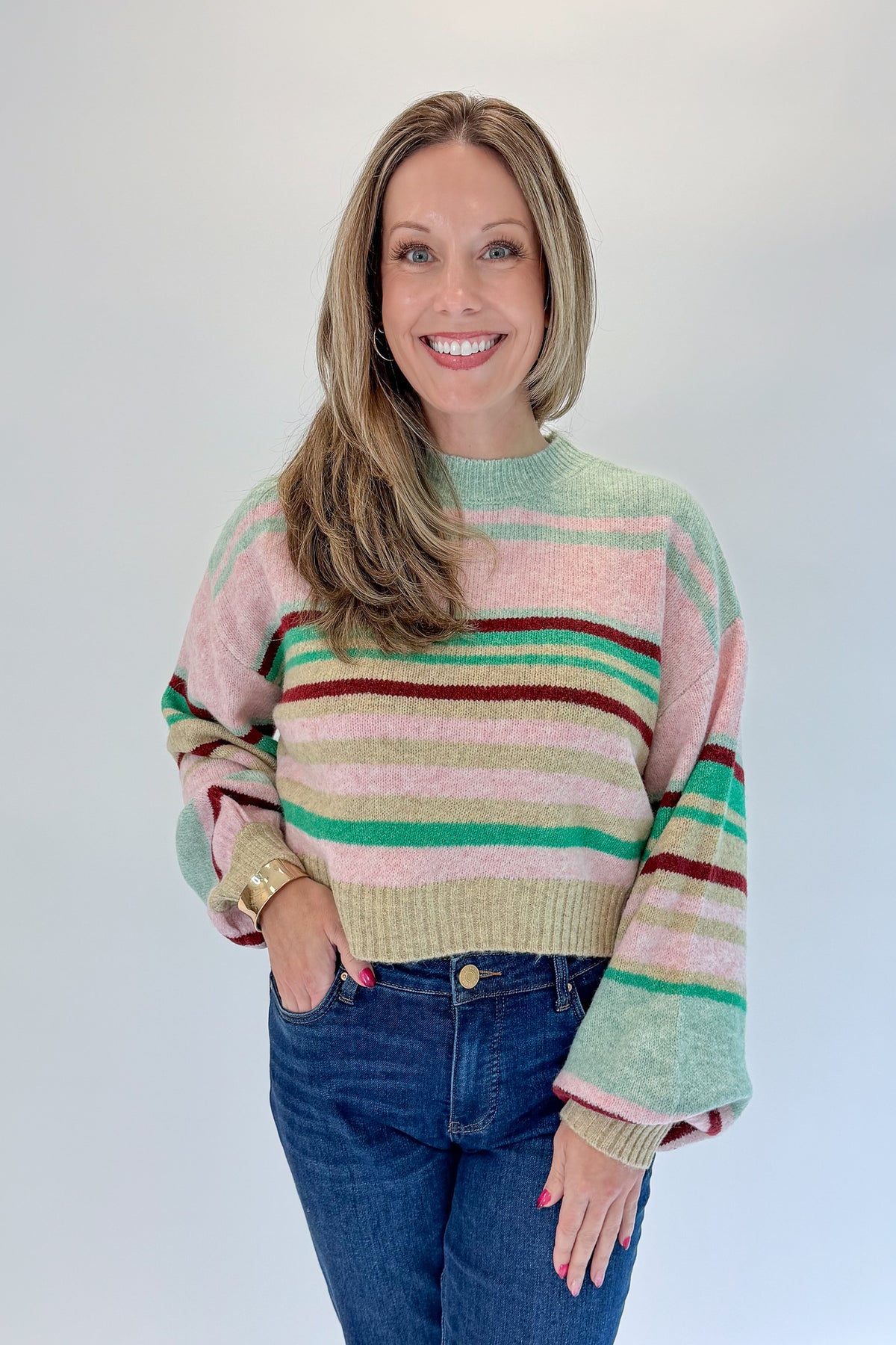 Front view of woman wearing Swagger Boutique’s Pink &amp; Multi Striped Sweater with jeans against white studio background.