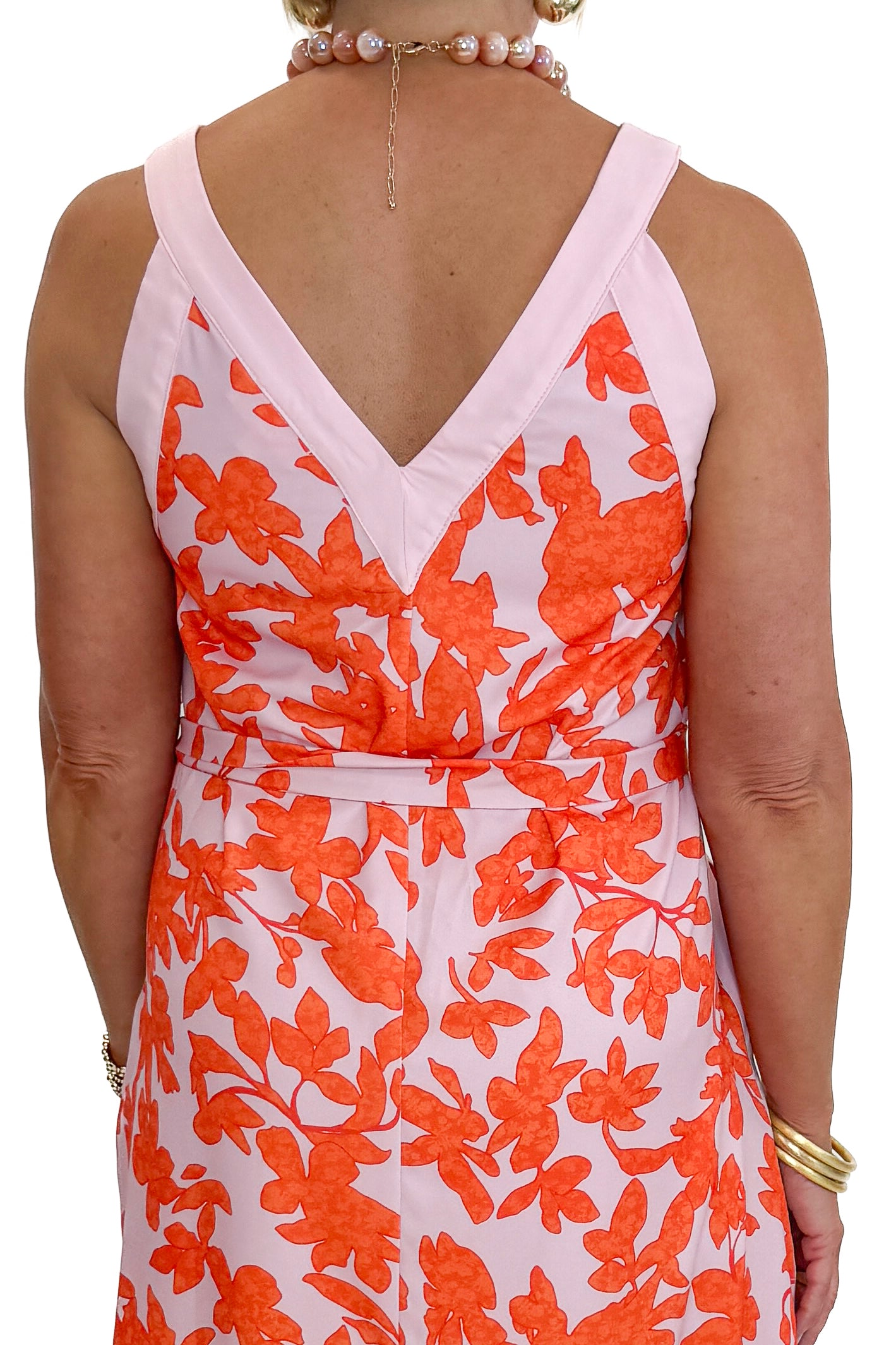 Back detail view of woman wearing Swagger Boutique’s Pink &amp; Orange Floral Midi Dress by Entro with heels against white studio background.