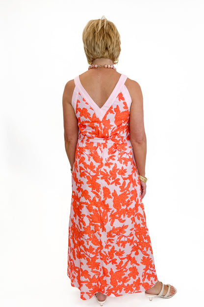 Back view of woman wearing Swagger Boutique’s Pink &amp; Orange Floral Midi Dress by Entro with heels against white studio background.