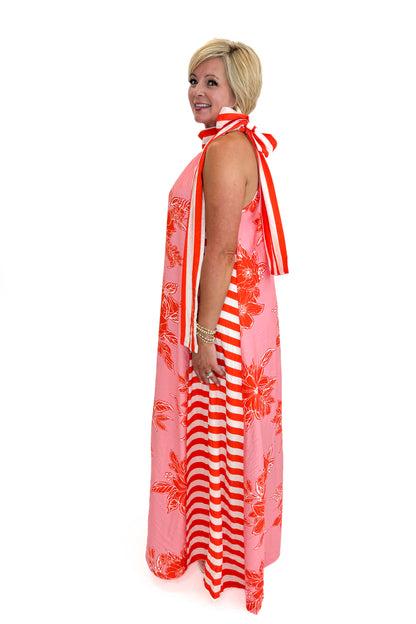 Side view of woman wearing Swagger Boutique’s Pink &amp; Orange Floral &amp; Stripe Maxi Dress by Entro with heels against white studio background.