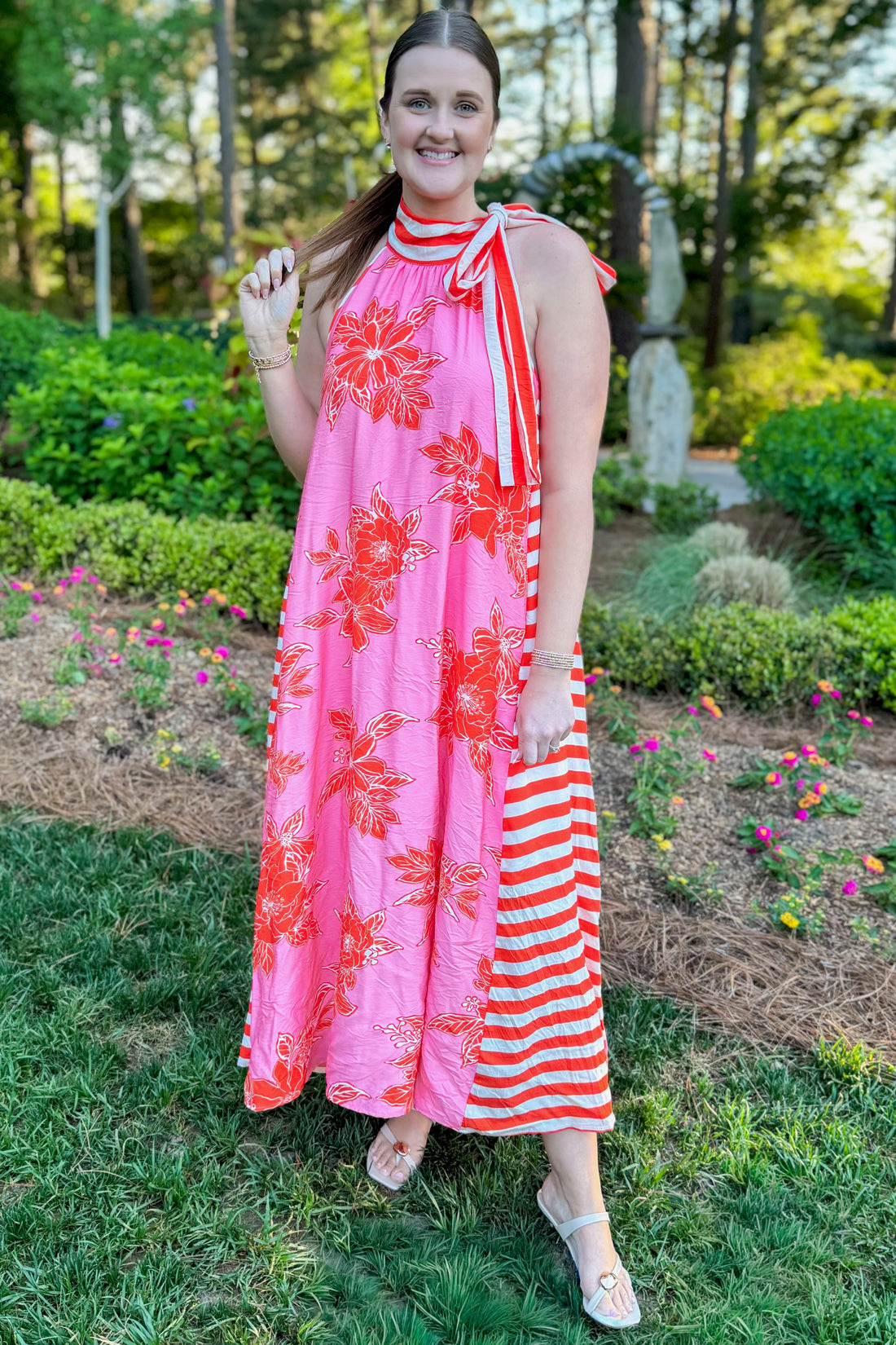 Front view of woman wearing Swagger Boutique’s Pink &amp; Orange Floral &amp; Stripe Maxi Dress by Entro with heels standing outside at a park.